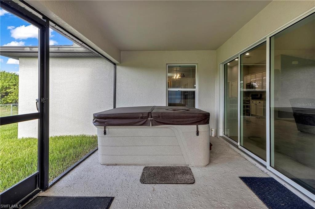 Screened patio with a covered hot tub, textured concrete flooring, and direct access to interior spaces via sliding glass doors