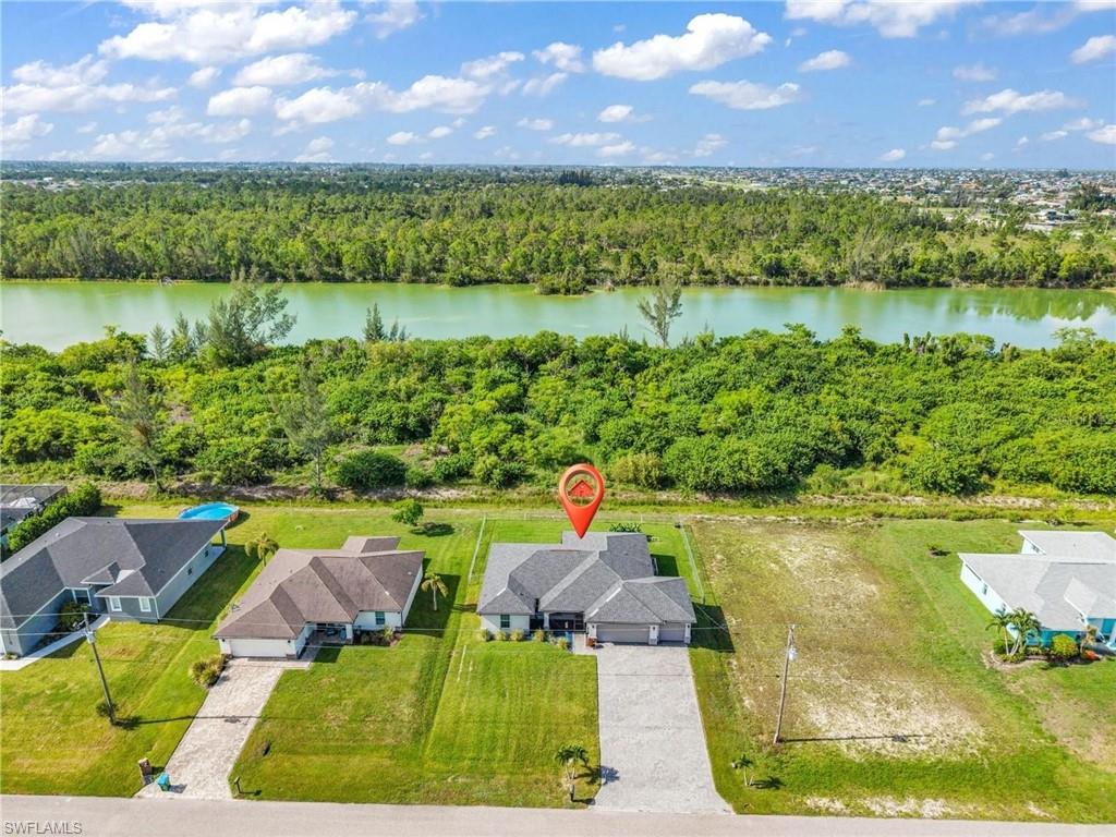 Aerial perspective showcasing a single-story home with an attached garage, a paved driveway, and a manicured lawn