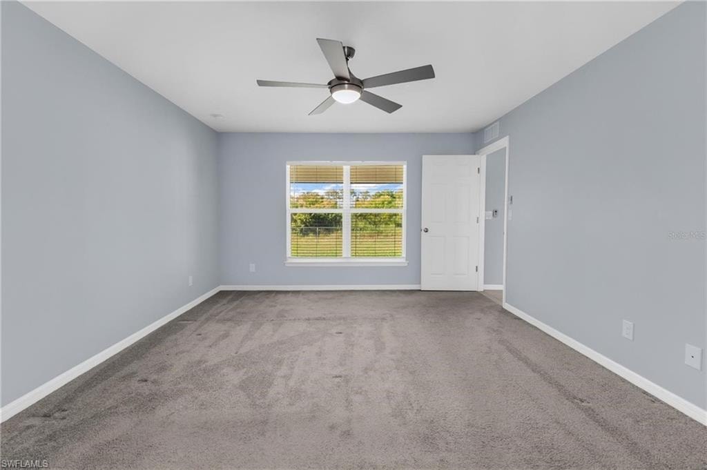 Spacious room featuring light blue walls and gray carpet flooring