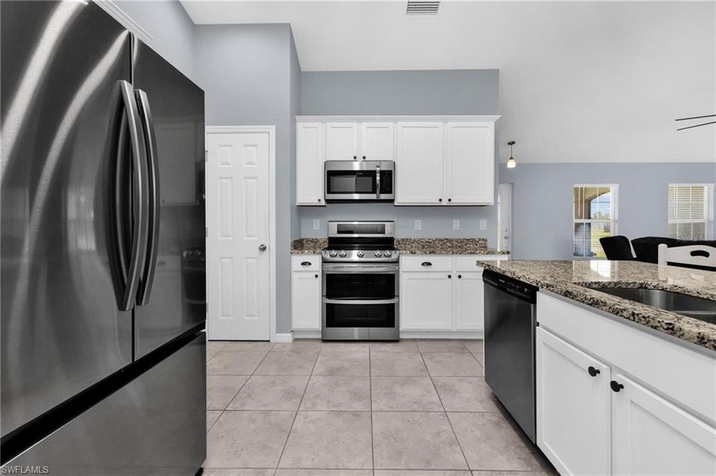 Modern kitchen featuring a stainless steel French-door refrigerator, white shaker cabinetry, granite countertops, and a full suite of stainless steel appliances including a double oven range and microwave