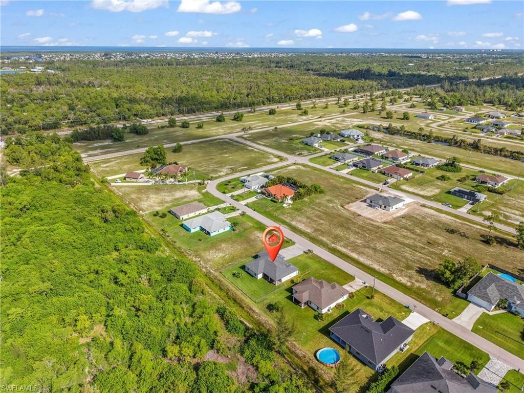 Aerial perspective showcasing the property within a developing neighborhood with established residential structures and undeveloped land parcels