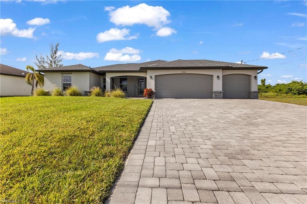 Contemporary stucco exterior with a stone accent facade, featuring a paver driveway, a three-car garage, and an inviting covered entry