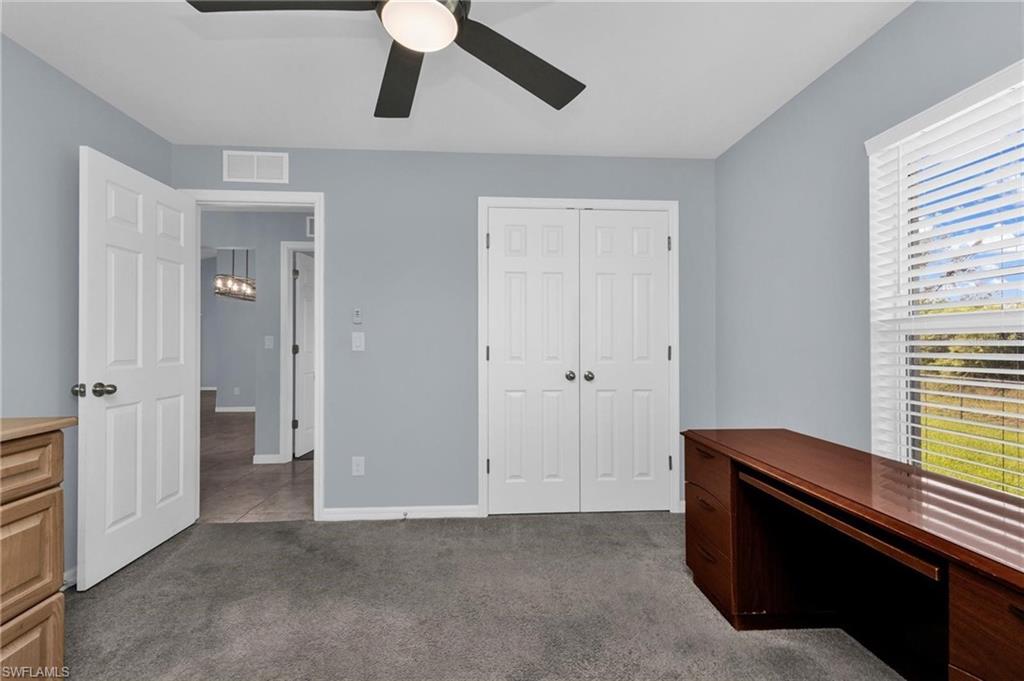 Room featuring light blue walls, gray carpet, a ceiling fan with integrated lighting, and a window with horizontal blinds