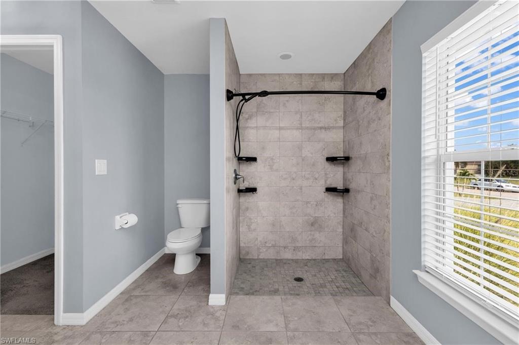 Walk-in shower with tiled walls and floor, complete with a dark-finish shower system and integrated shelving