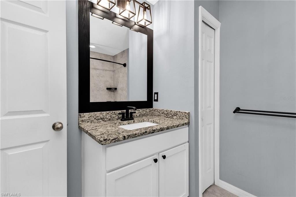 Bathroom vanity featuring a granite-style countertop with an integrated sink, white cabinetry, and matte black hardware