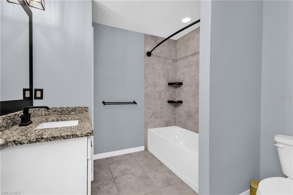 Bathroom featuring a white vanity with a granite-style countertop and undermount sink, matte black faucet, and a large wall mirror