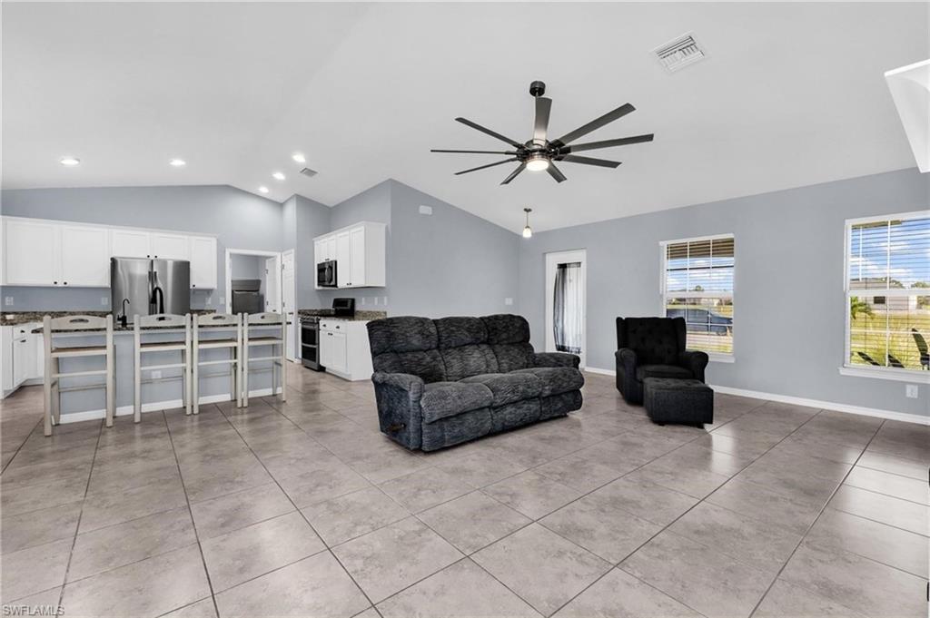 Open-concept living space with vaulted ceilings, large format tile flooring, and light gray wall tones