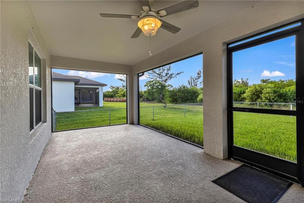 Expansive screened-in lanai with a concrete floor, overhead ceiling fan with light fixture, and direct outdoor access