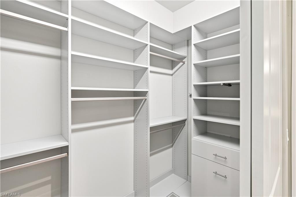 Built-in white custom closet system featuring multiple shelving units, integrated drawers with brushed nickel hardware, and multiple hanging rods