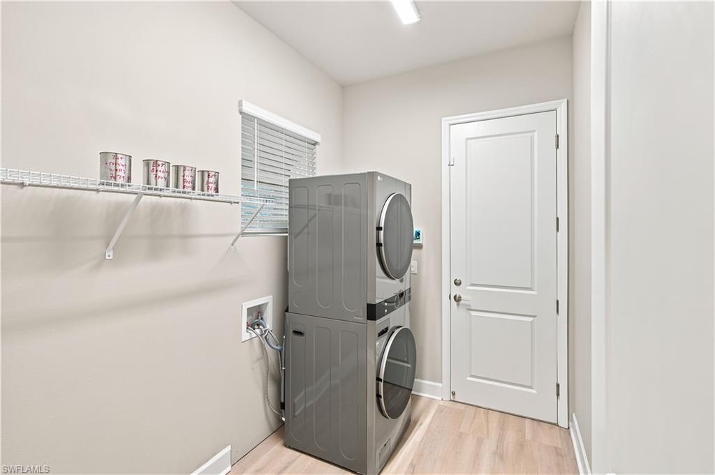 Dedicated laundry space featuring light wood-finish flooring, a window with blinds, and white wire shelving