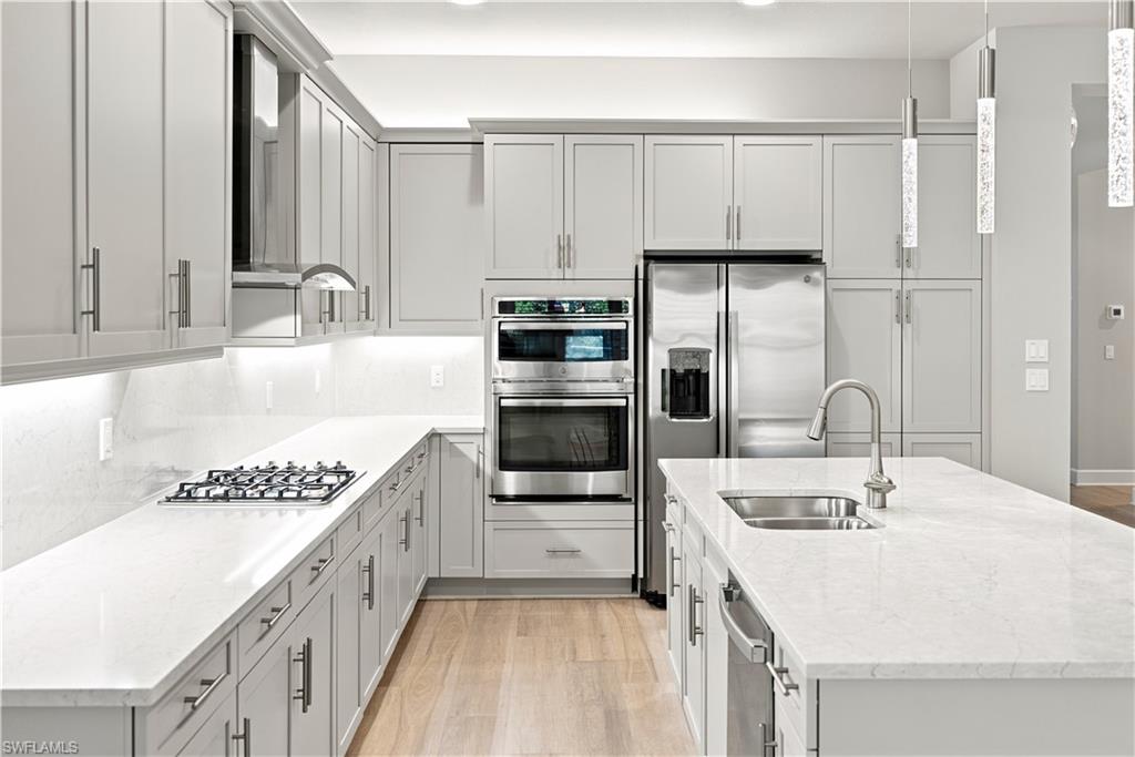 Bright kitchen featuring light cabinetry, stainless steel appliances, a gas cooktop, and an island with an undermount sink