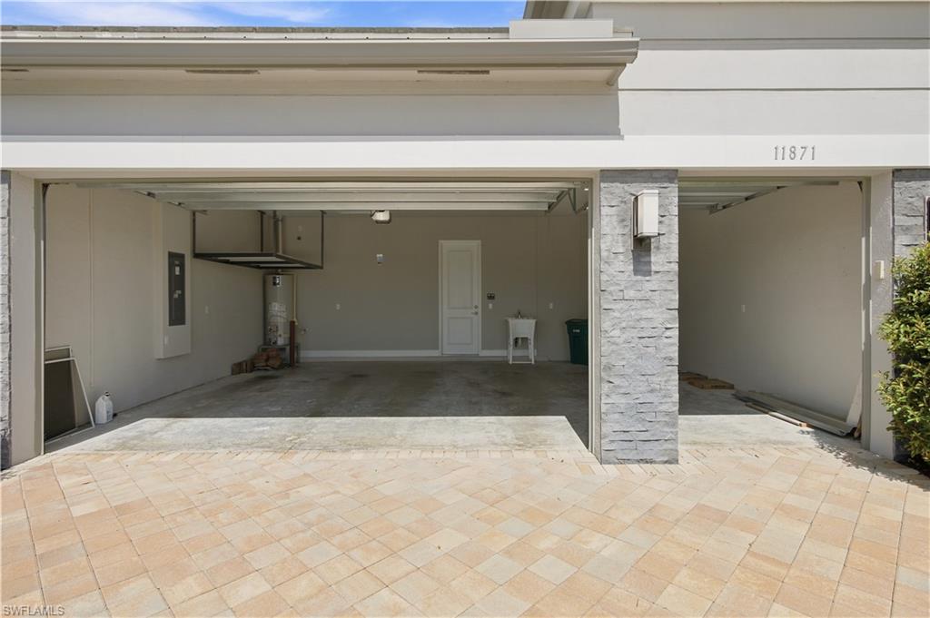 Two-car garage + Golf Cart garage featuring a utility sink, overhead storage and a paved driveway entrance