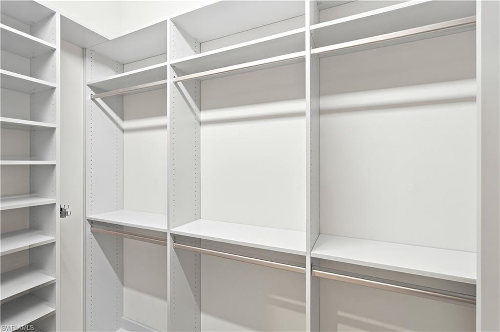 Custom closet system featuring white shelving and chrome hanging rods