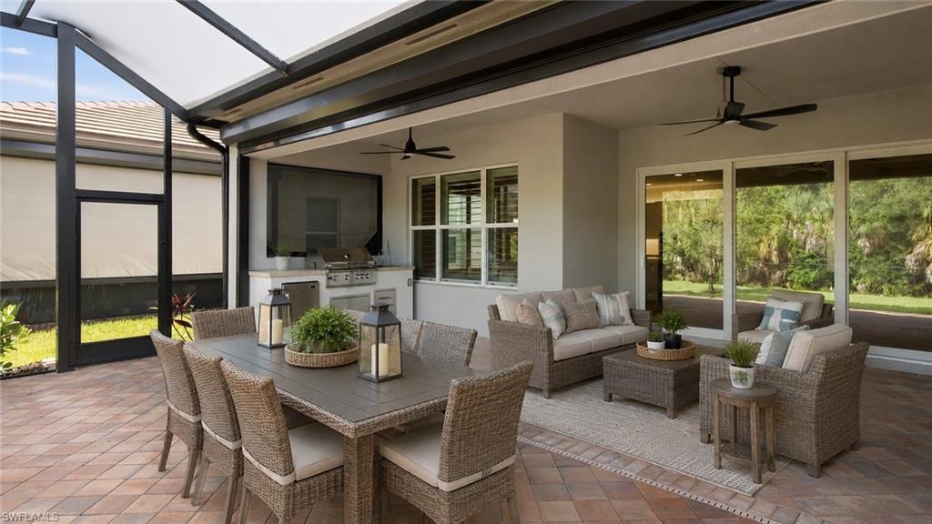 Room Digitally Staged  Extended Screened lanai featuring a built-in outdoor kitchen, recessed lighting, outdoor kitchen, ceiling fans, and a paver patio