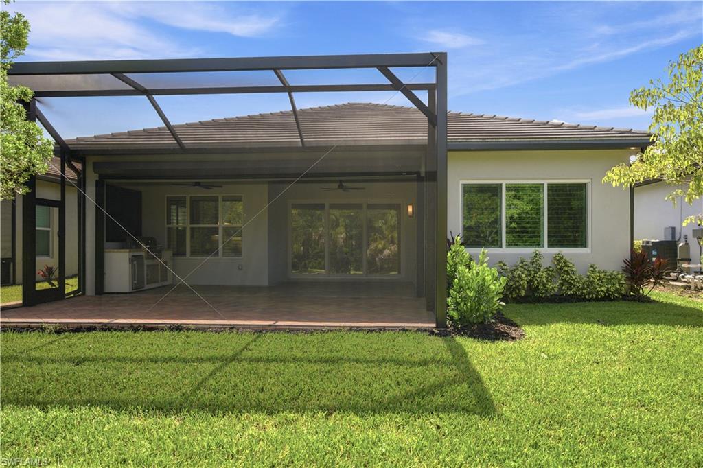 Expansive screened lanai featuring terra cotta tile flooring, an outdoor kitchen area, and ceiling fans