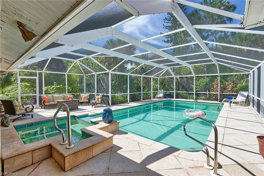 View of swimming pool featuring outdoor lounge area, glass enclosure, and a patio