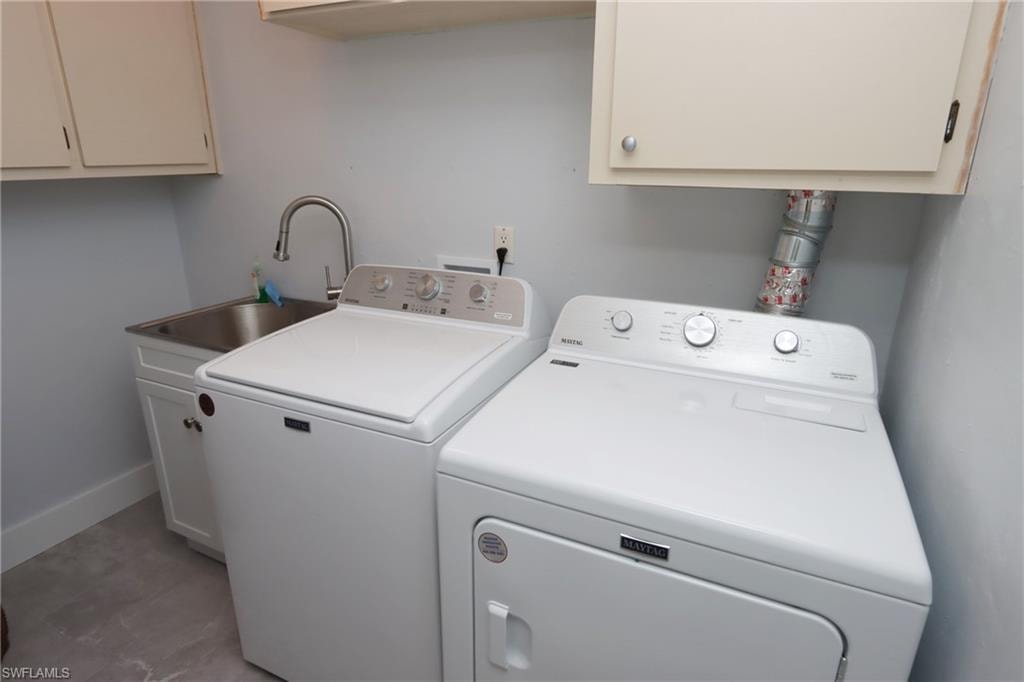 Washroom with separate washer and dryer, sink, tile flooring, and cabinets