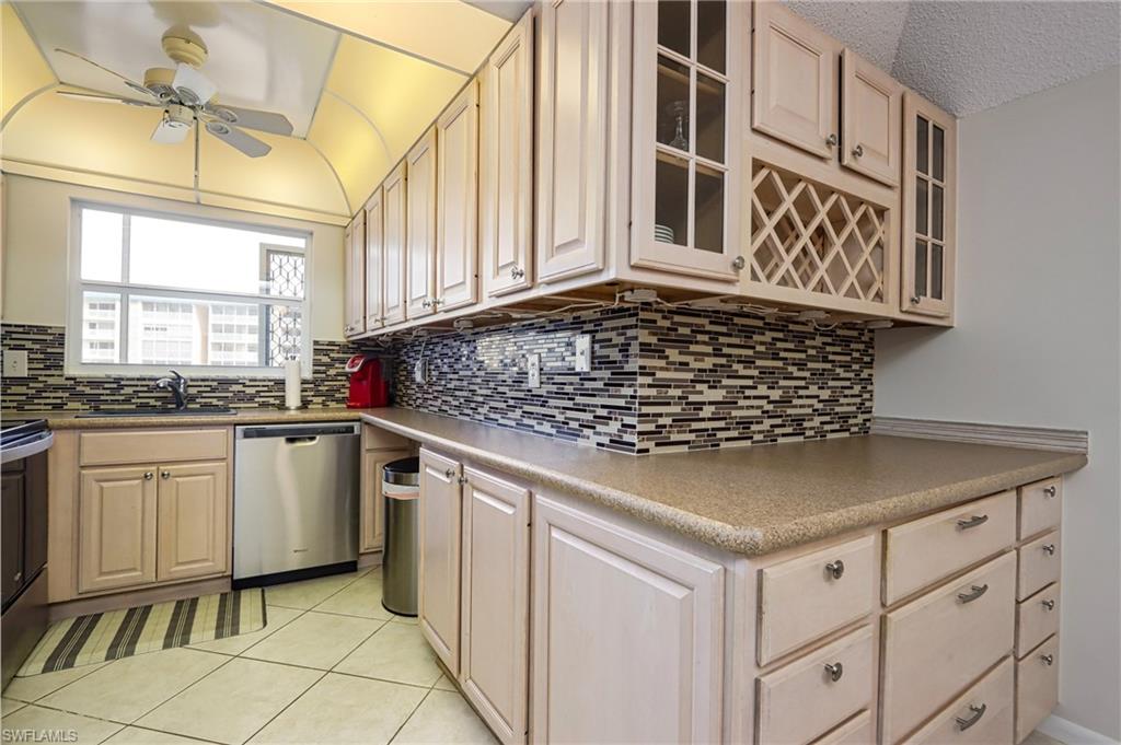 Kitchen with ceiling fan, sink, tasteful backsplash, dishwasher, and light tile floors