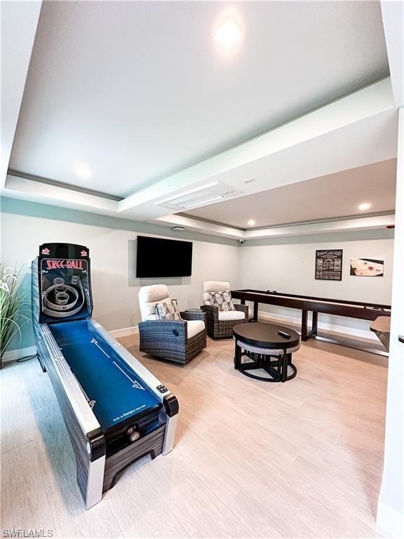 Recreation room featuring wood finished floors, a tray ceiling, and recessed lighting