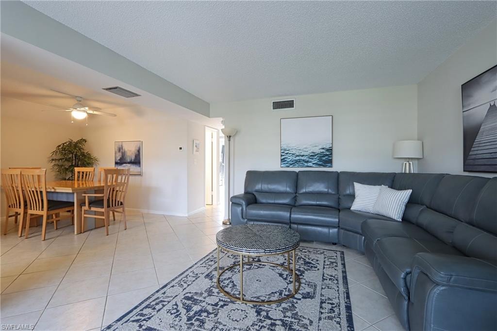 Tiled living room with ceiling fan and a textured ceiling