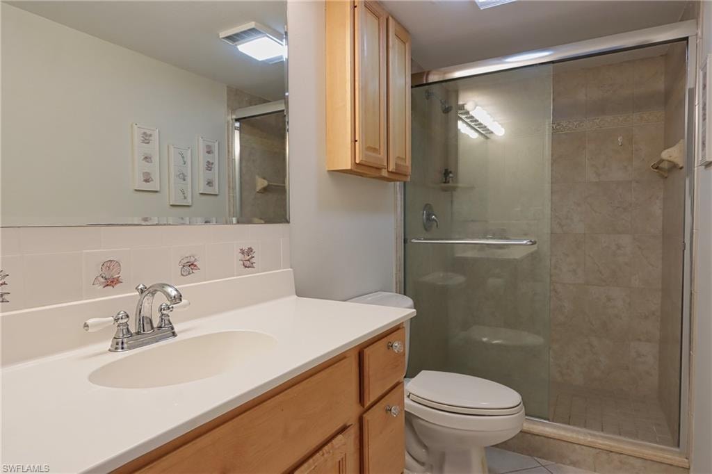 Bathroom featuring an enclosed shower, tile flooring, large vanity, and toilet