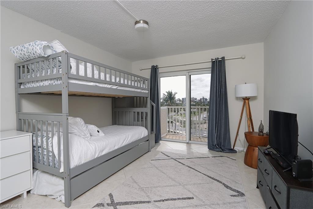 Tiled bedroom with a textured ceiling and access to exterior