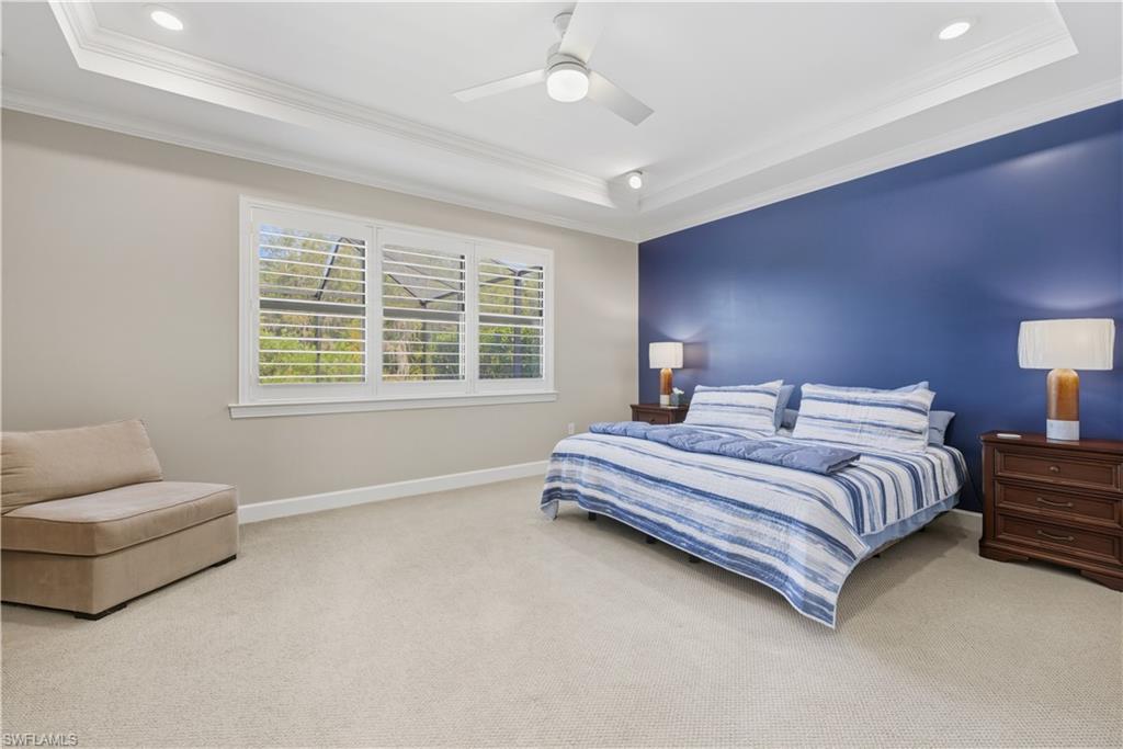 Carpeted bedroom featuring a raised ceiling, crown molding, a ceiling fan, and recessed lighting