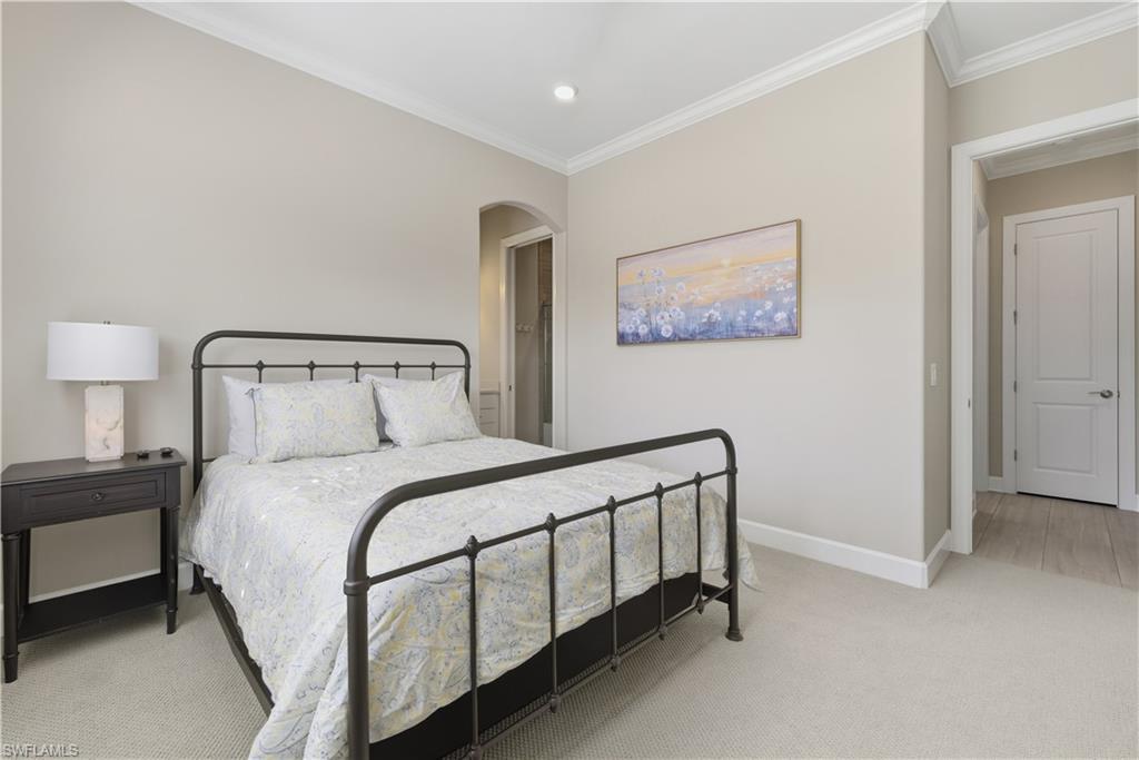 Bedroom featuring light carpet, crown molding, arched walkways, and recessed lighting