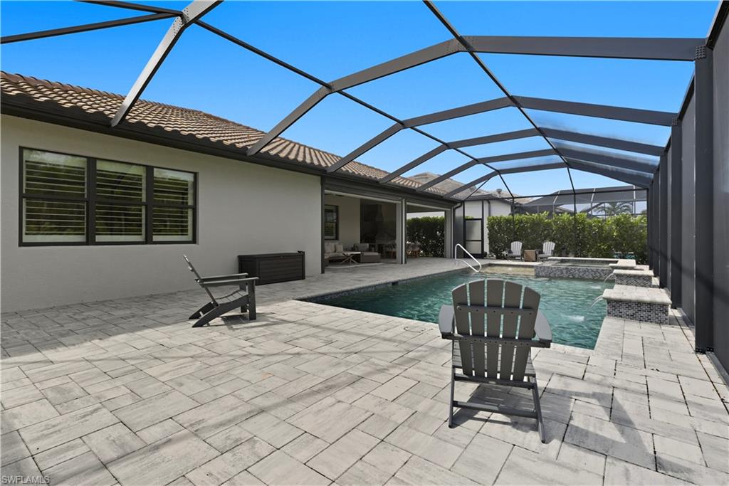 View of pool featuring a sunroom, a lanai, a patio, and a pool with connected hot tub