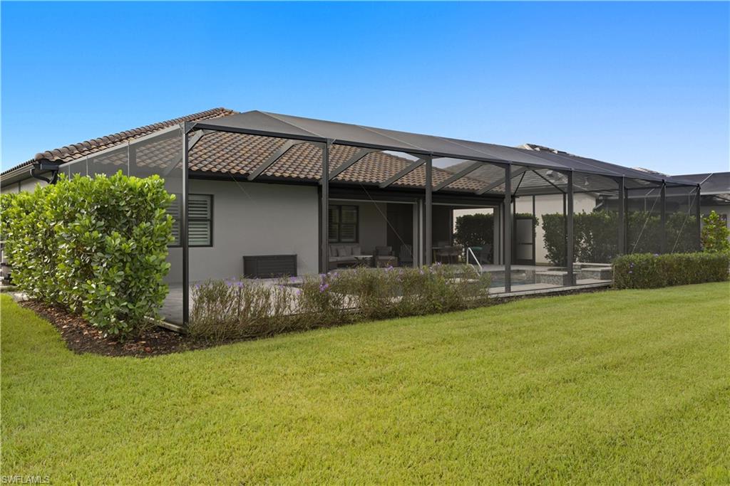 Back of property featuring a lanai, a sunroom, a lawn, and stucco siding