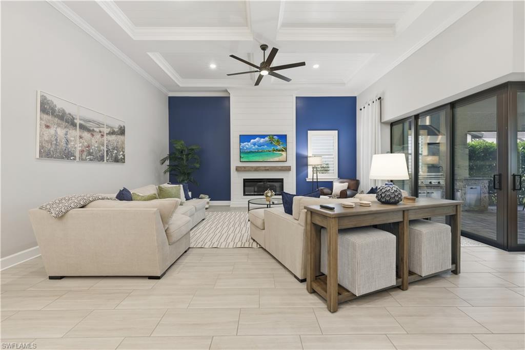 Living room featuring coffered ceiling, beam ceiling, ceiling fan, a large fireplace, and ornamental molding