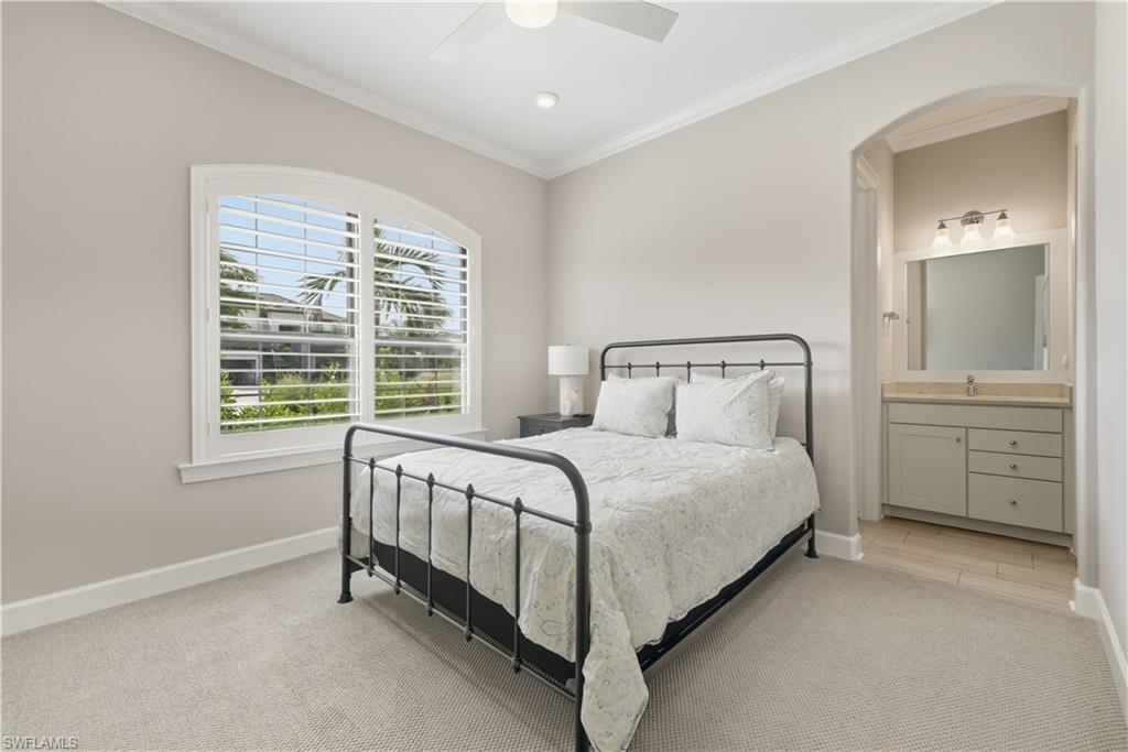 Bedroom with ornamental molding, ceiling fan, connected bathroom, and light colored carpet