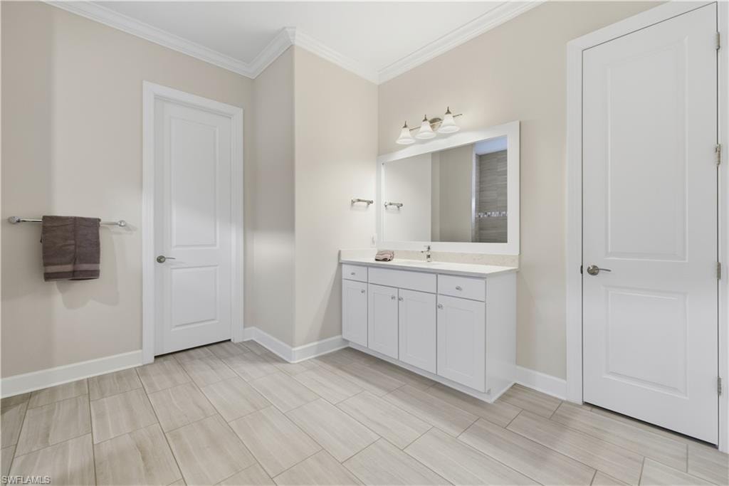 Bathroom featuring vanity, crown molding, and wood finish floors