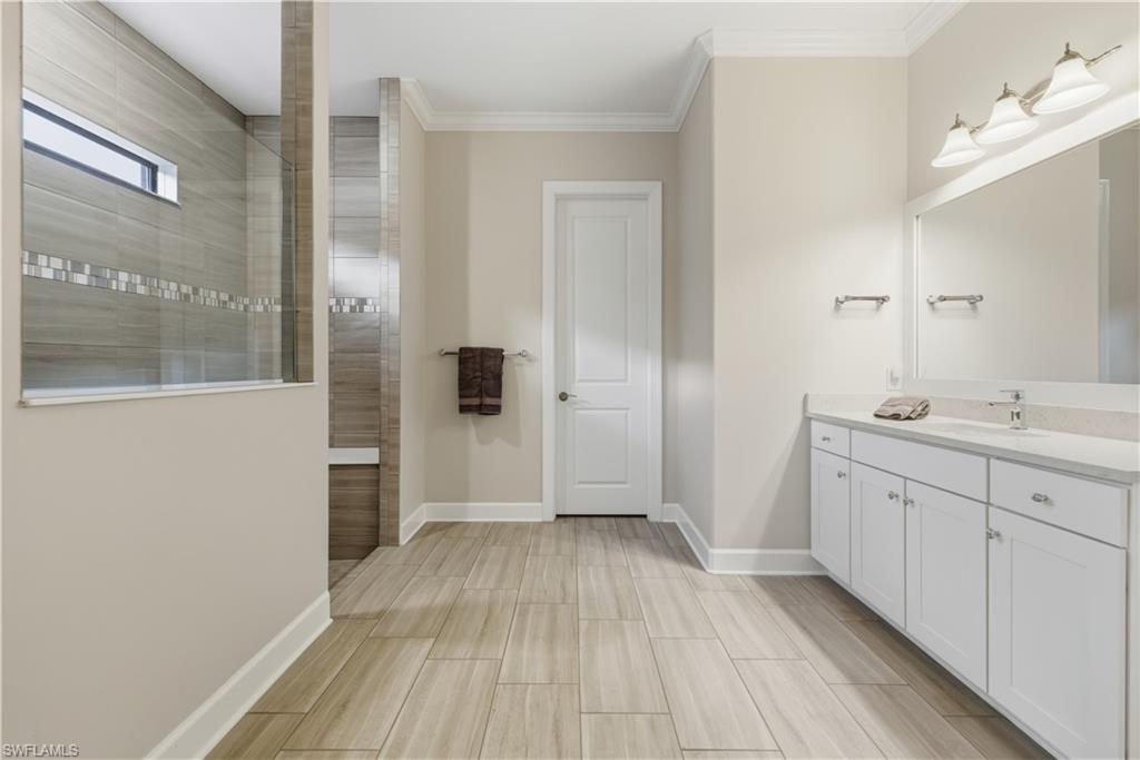 Bathroom with vanity, walk in shower, ornamental molding, and wood finish floors
