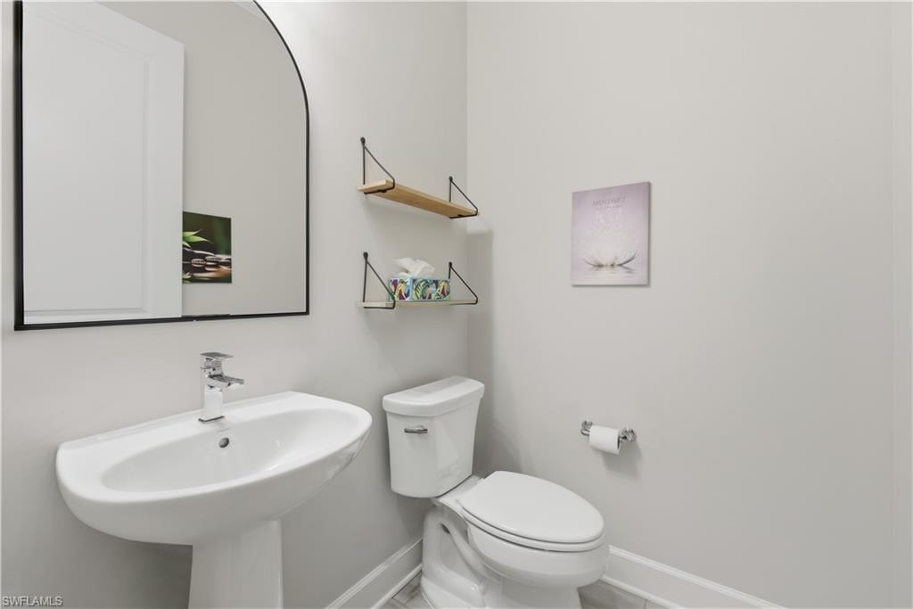 Half bathroom with toilet and baseboards