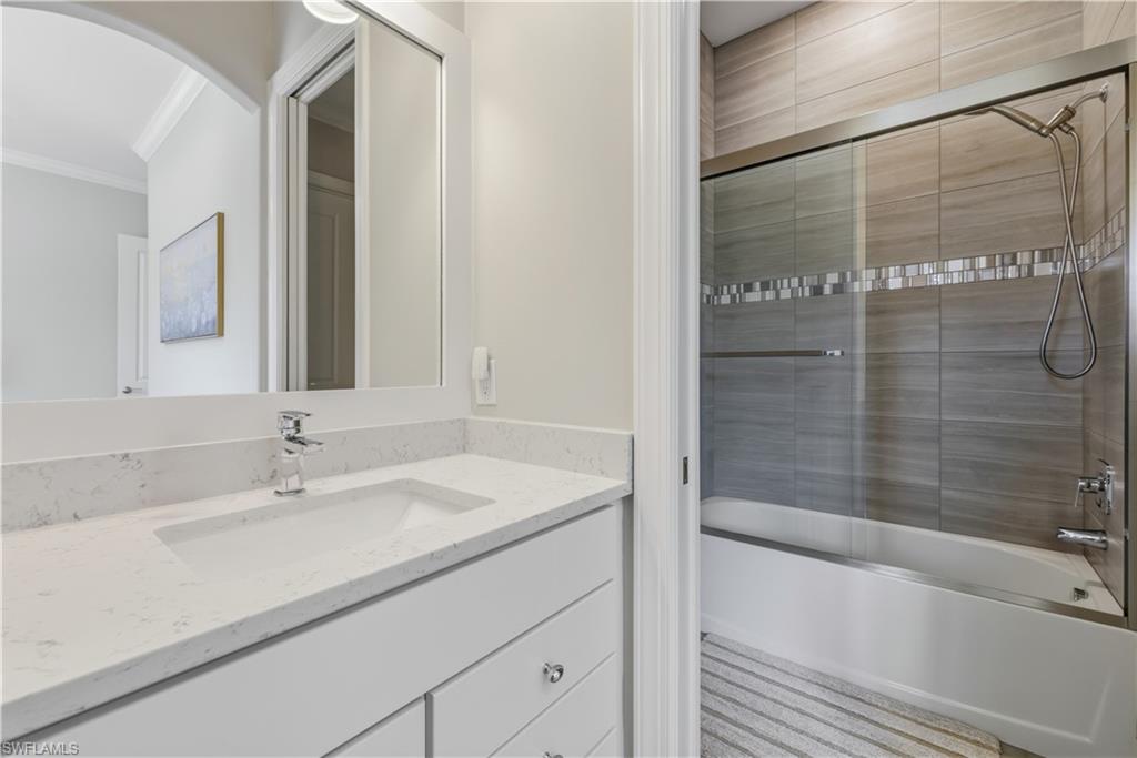 Full bathroom with enclosed tub / shower combo, vanity, and crown molding