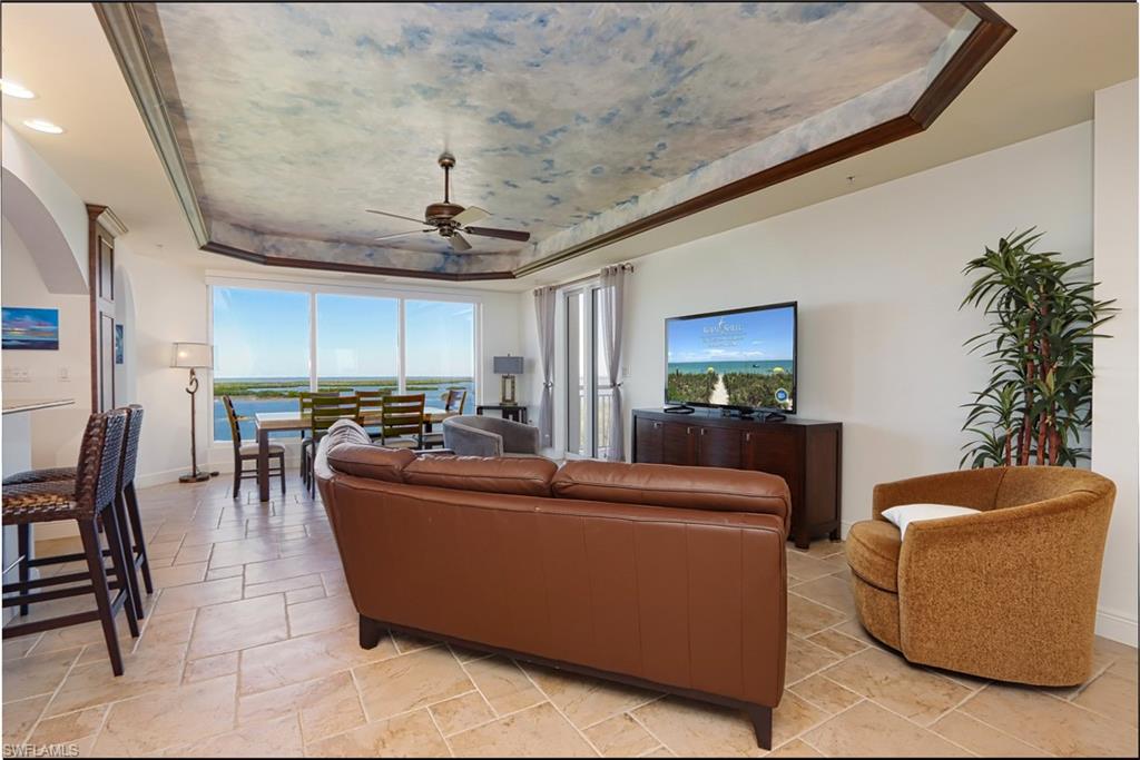 Tiled living room featuring a tray ceiling and ceiling fan