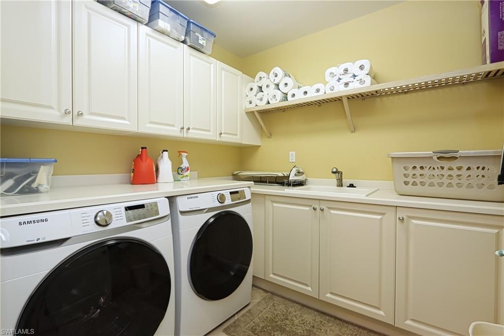 Washroom featuring cabinets, washer and clothes dryer, sink, and light tile patterned floors