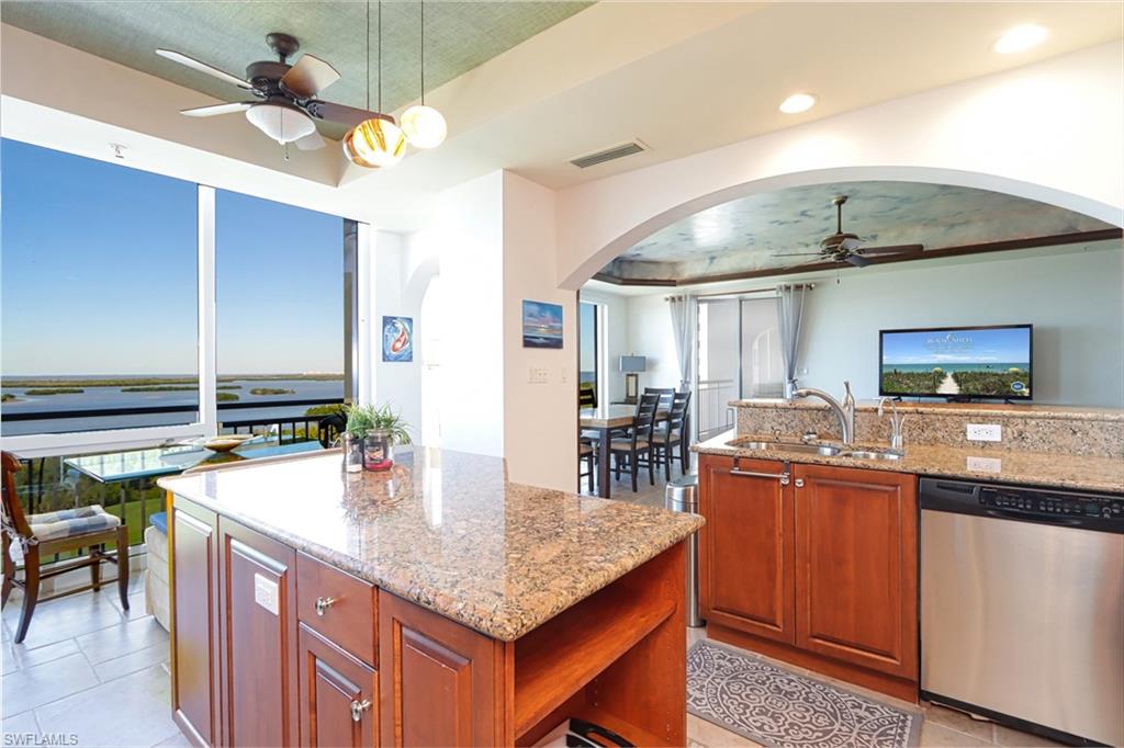 Kitchen featuring dishwasher, ceiling fan, a raised ceiling, and a center island
