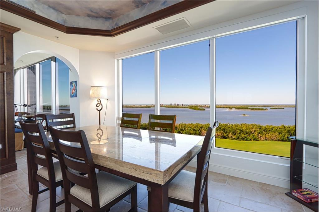 Tiled dining space with a tray ceiling and a water view