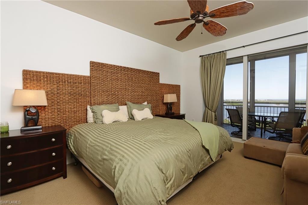 Carpeted bedroom with a water view, ceiling fan, and access to exterior