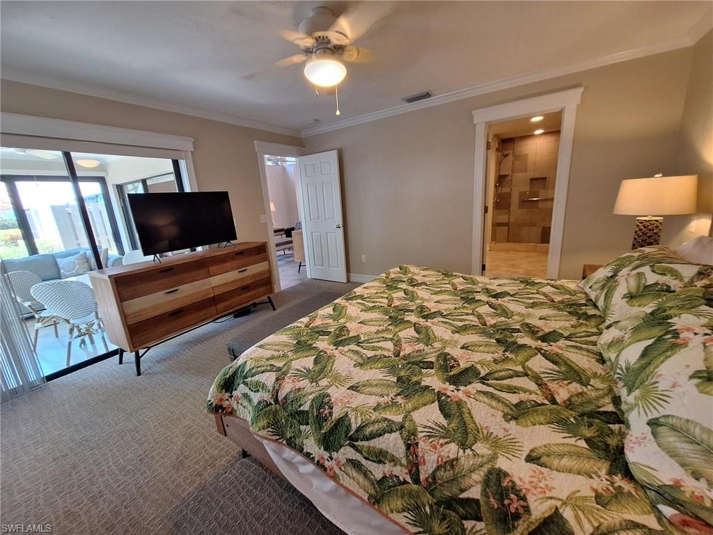 Bedroom featuring ceiling fan, ornamental molding, carpet floors, and ensuite bathroom