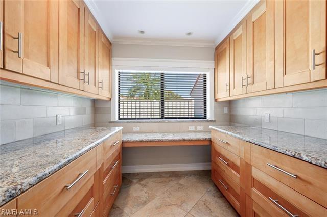 Upgraded Kitchen featuring light stone countertops and desk area tasteful backsplash, and light tile flooring