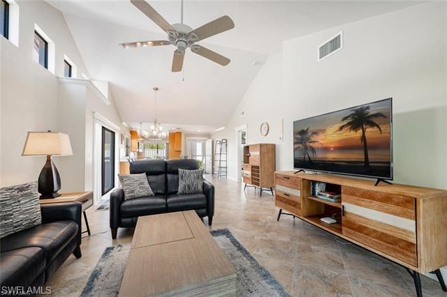 Tiled living room with high vaulted ceiling and ceiling fan with notable chandelier. Seats 6.