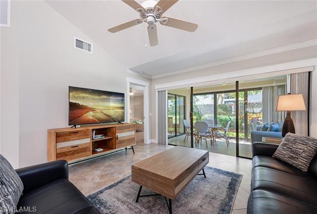 Living room featuring tile flooring, ceiling fan, and lofted ceiling