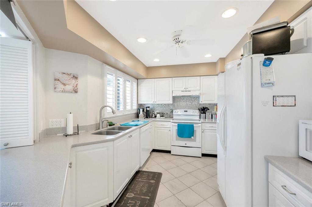 Community Kitchen with white appliances, sink, white cabinetry, and ceiling fan