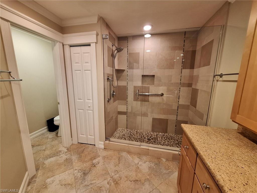 Bathroom featuring tile flooring, an enclosed shower, vanity, and toilet