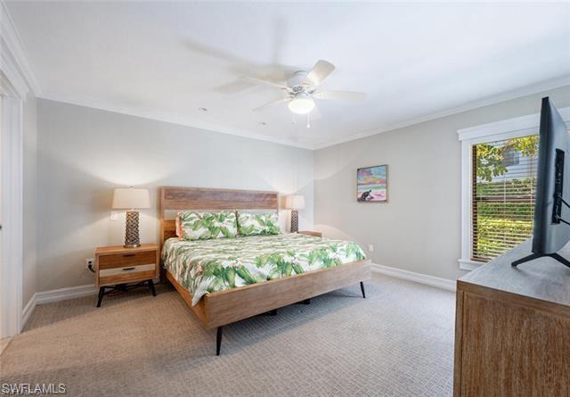 Primary Carpeted bedroom with ceiling fan  walkout and crown molding