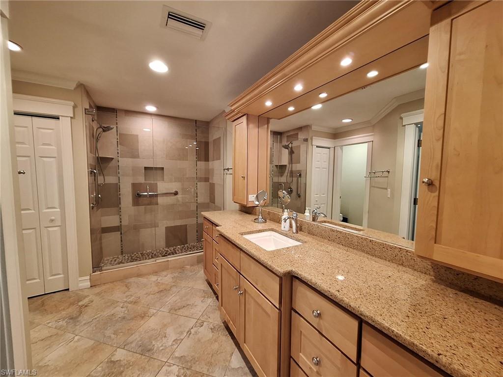 Bathroom with tile flooring, walk in shower, ornamental molding, and large vanity