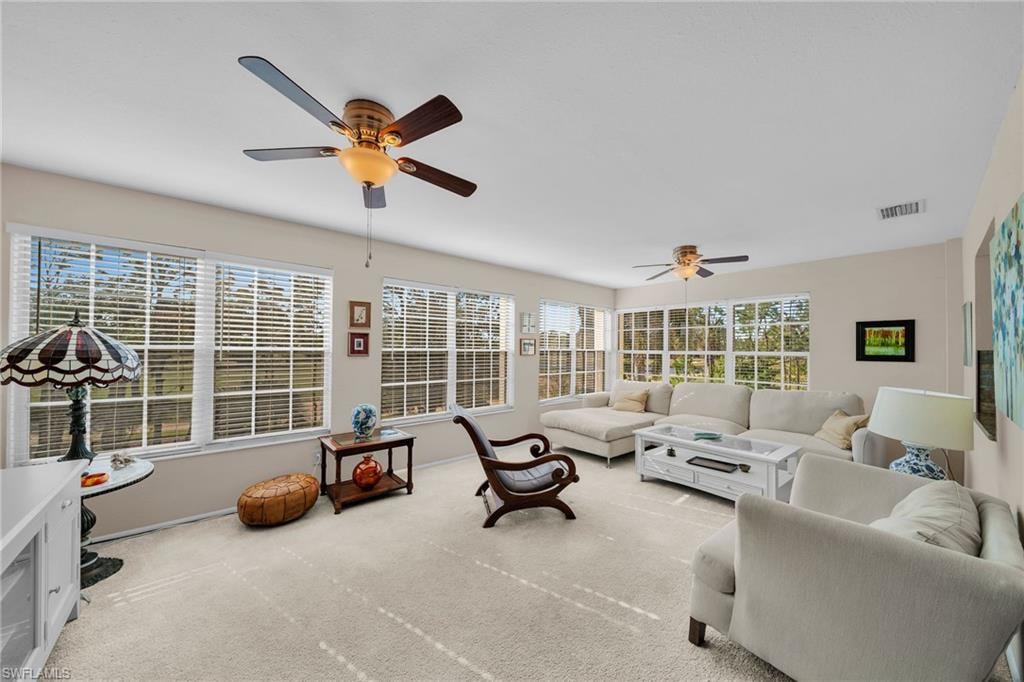 Bright living area featuring carpeted flooring and multiple windows with white blinds